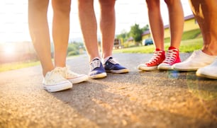 Legs and sneakers of teenage boys and girls standing on the sidewalk