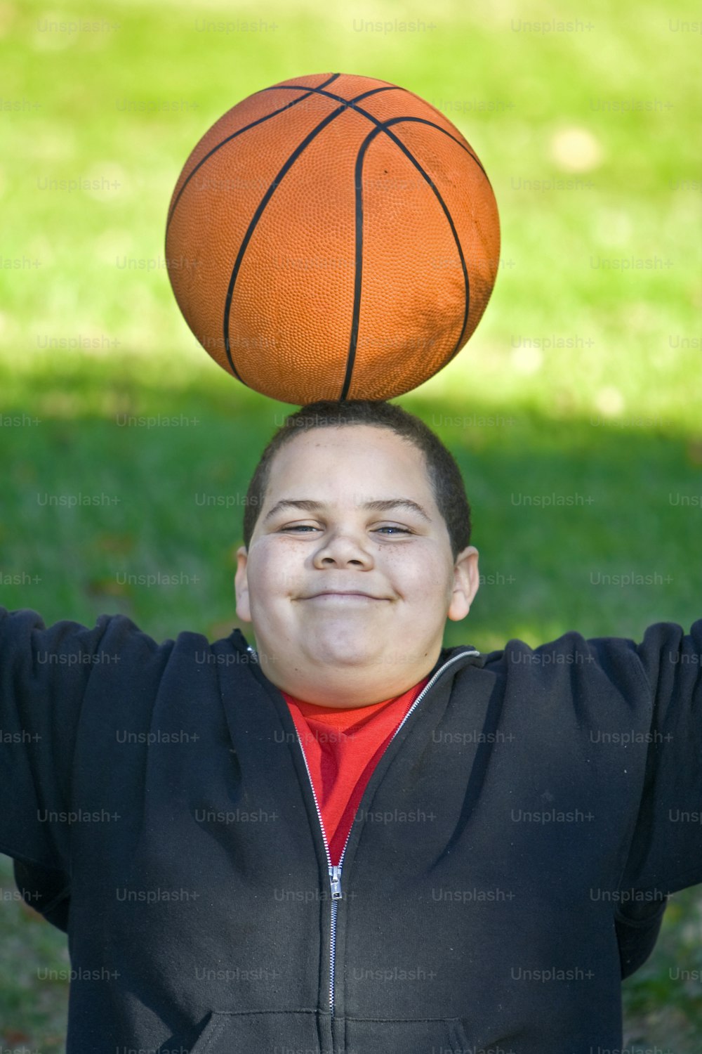 Junge mit Basketball balanciert auf dem Kopf