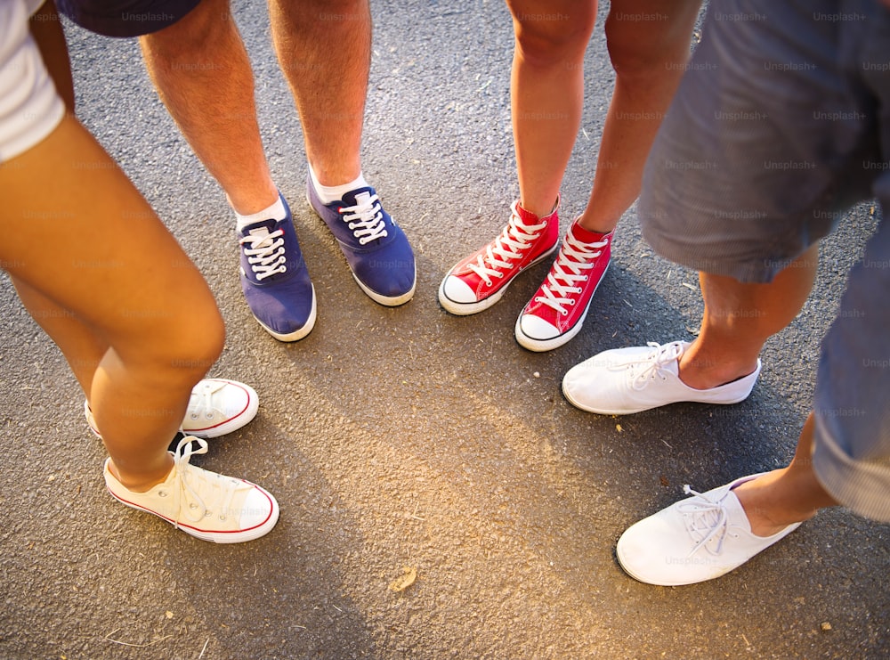 Piernas y zapatillas de adolescentes de ambos sexos parados en la acera