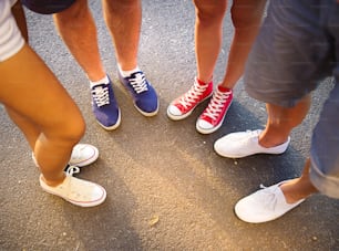Piernas y zapatillas de adolescentes de ambos sexos parados en la acera