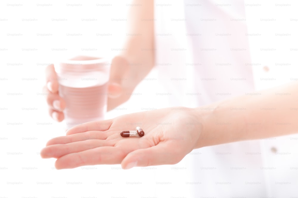 doctor holding a pill and a glass of water, close-up