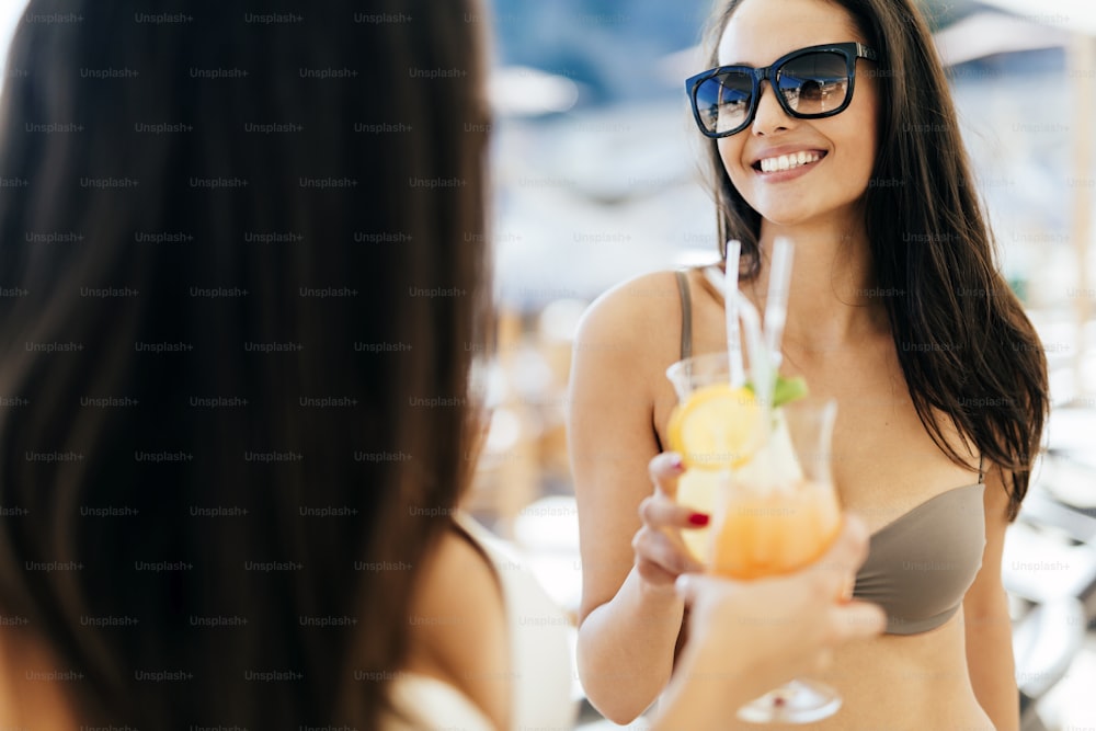 Mujeres hermosas en la playa soleada disfrutando de cócteles