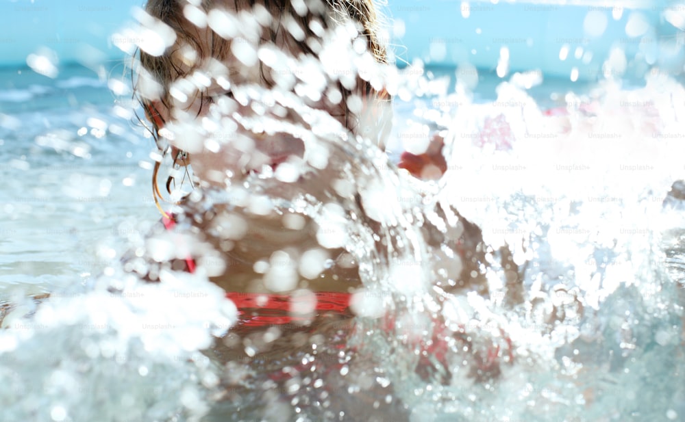 Little girls having fun in the pool and splashes water everywhere.