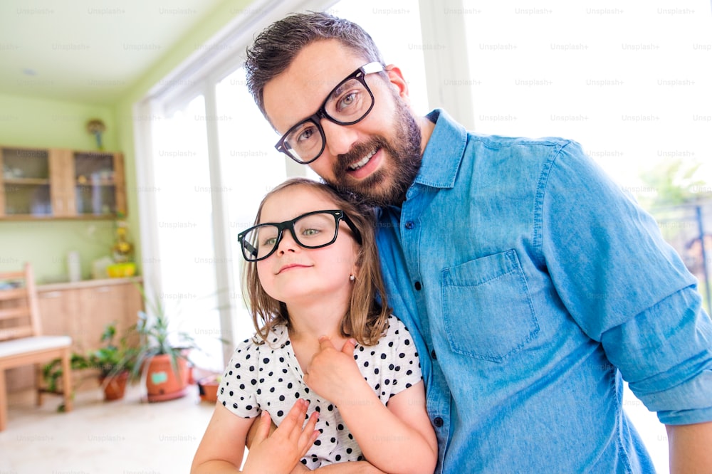 Father with his little daughter in black hipster eyeglasses, sunny day indoors