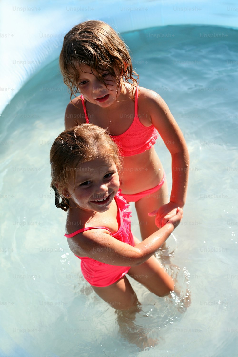 Two little Caucasian girls playing in the swimming pool.