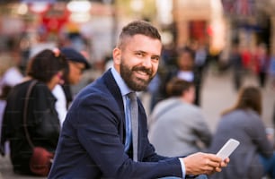 Unrecognizable manager sitting on stairs on sunny Piccadilly Circus, London, working on smart phone