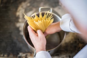 Chef che inserisce la pasta nella pentola della cucina