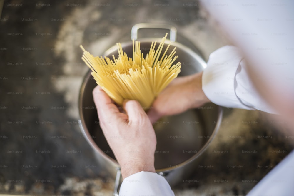 Chef inserting pasta to the kitchen pot