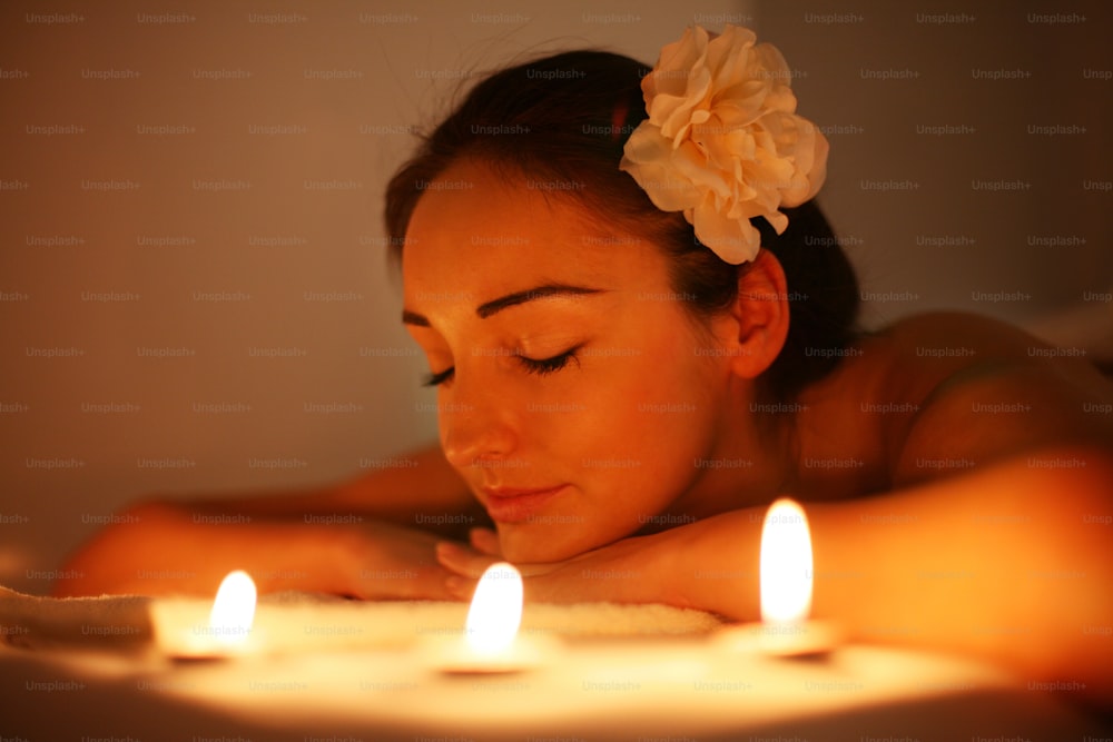 Mulher nova em um centro de spa. Deitado em uma mesa de massagem em um belo entorno. Luz ambiente e lâmpadas piloto utilizadas.