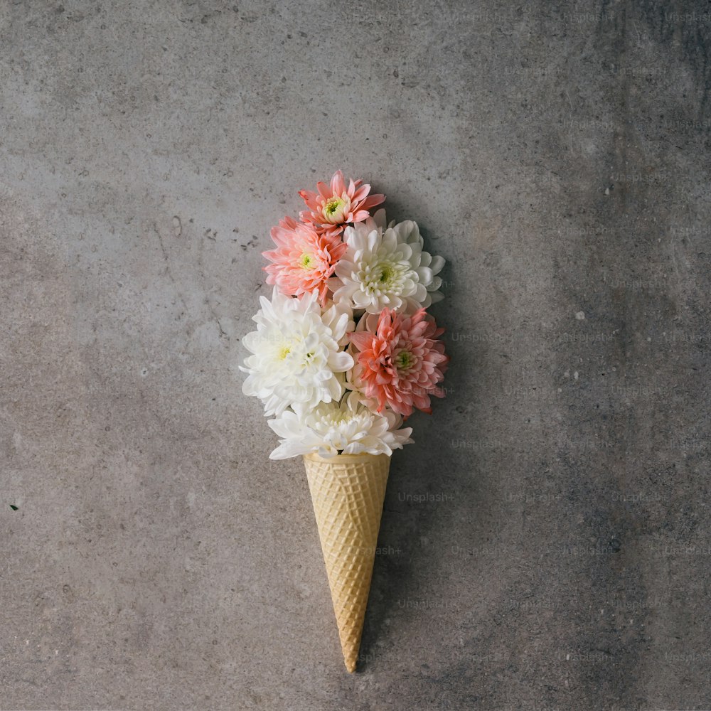 Pink and white flowers in ice cream cone on marble background. Minimal concept. Flat lay.