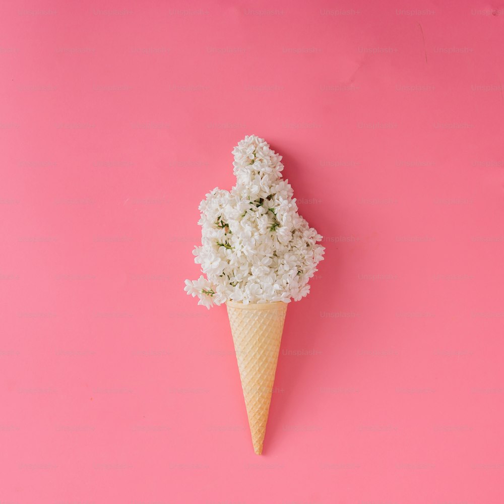 Lilac flower in ice cream cone on pink background. Minimal concept. Flat lay.