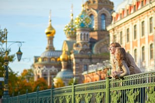 Happy young romantic couple walking together in St. Petersburg, Russia on a warm sunny autumn day near the Church of the savior on Blood