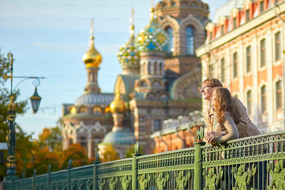 Happy young romantic couple walking together in St. Petersburg, Russia on a warm sunny autumn day near the Church of the savior on Blood