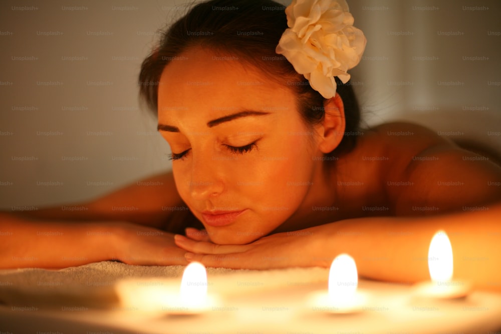 Young woman in a spa center. Lying on a massage table in beautiful surrounding. Ambient light and pilot lamps used.