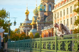 Happy young romantic couple walking together in St. Petersburg, Russia on a warm sunny autumn day near the Church of the savior on Blood
