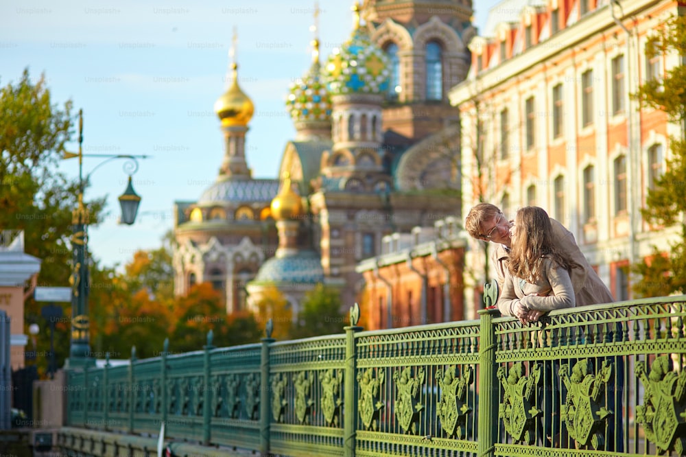 Happy young romantic couple walking together in St. Petersburg, Russia on a warm sunny autumn day near the Church of the savior on Blood