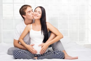 Happy young man kissing her pregnant smiling wife
