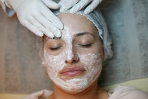 Mujer joven en un centro de spa. Acostada en una camilla de masaje con una mascarilla en la cara.