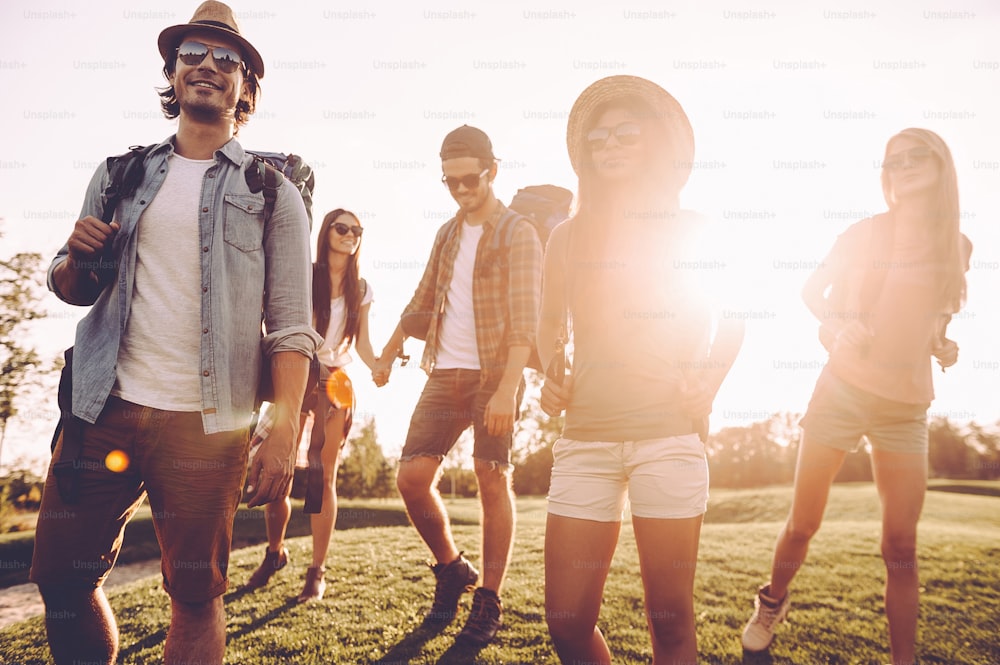 Low angle view of beautiful young people with backpacks walking together and looking happy