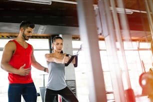 Personal Trainer gibt Anweisungen für Schüler im Fitnessstudio