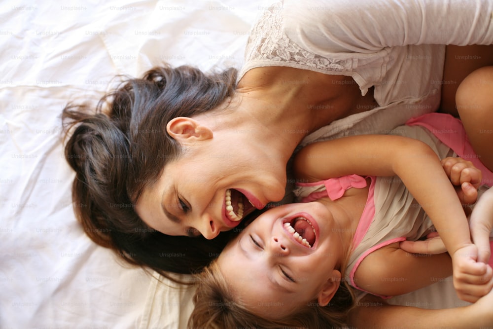 Mother with her daughter enjoy in bed at the morning.
