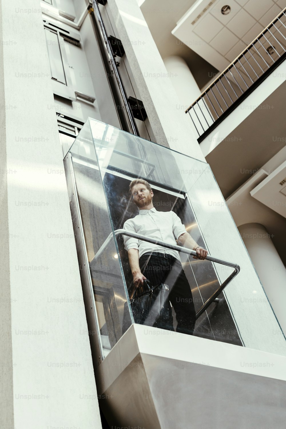 Businessman taking modern glass elevator to the upper floors