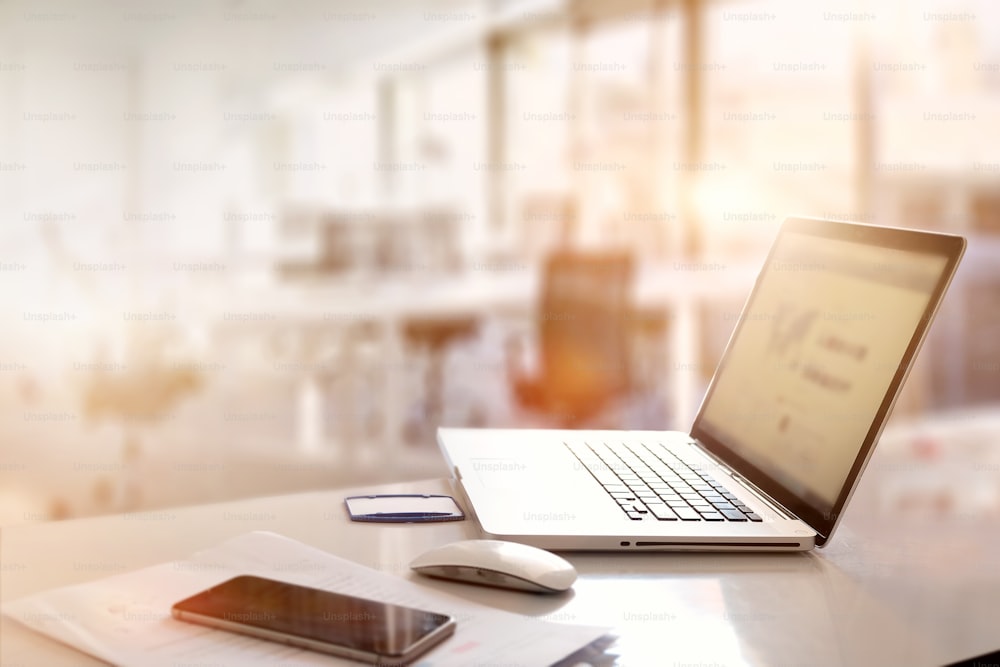 office desk with laptop smart phone and business office background.