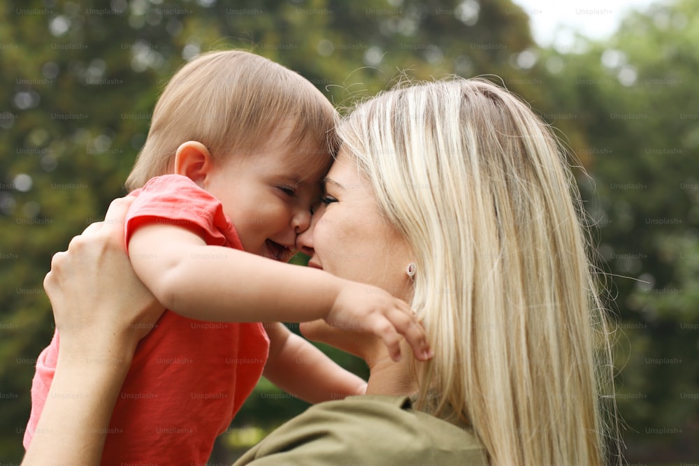 Young mother touching with nose her baby daughter and both smiling.