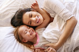 Mother with her daughter enjoy in bed at the morning. Space for copy.