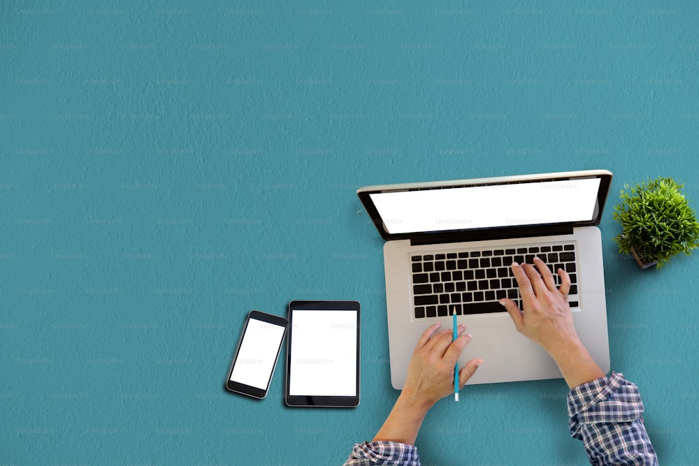 Work office desk with Blank Screen of Tablet ,Smart phone and man using computer laptop. Top view.