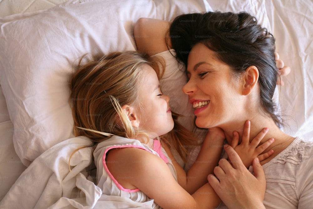 Mother with her daughter enjoy in bed.