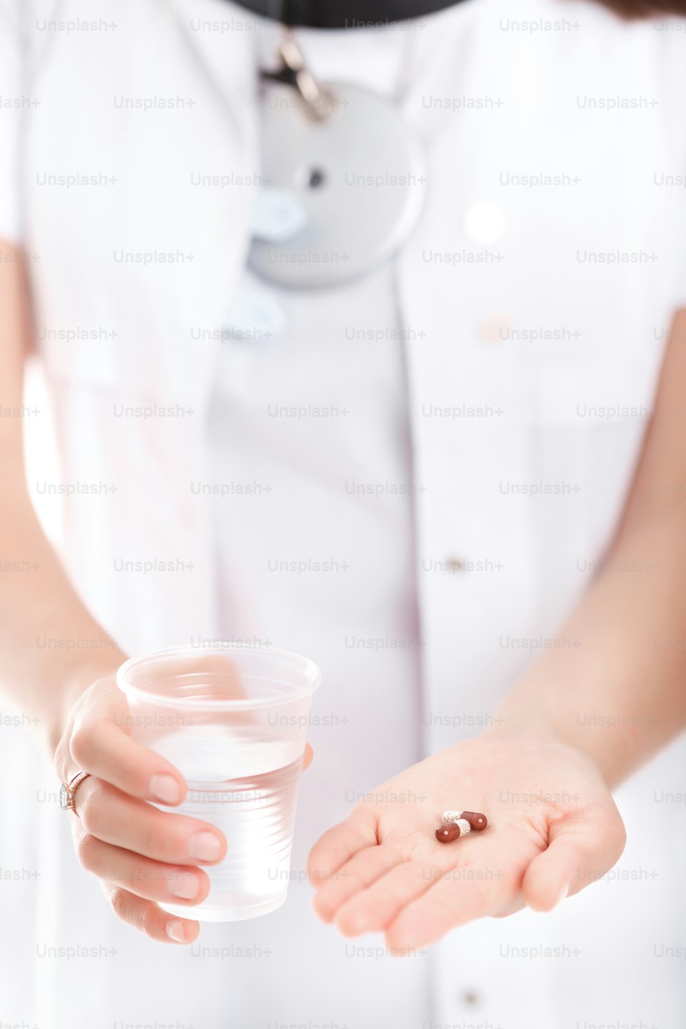 doctor holding a pill and a glass of water, close-up
