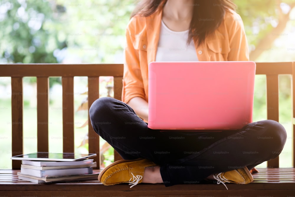 コンピューターを使用している若い女性。教育、学習、またはフリーランスの屋外作業やリラクゼーションのコンセプトのアイデアの背景。