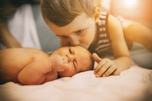 Brother kissing sweet little newborn sister