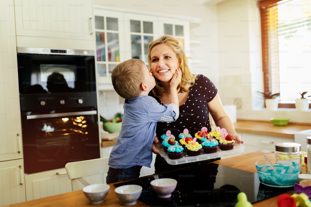 Child helping mother prepare muffins in kitchen