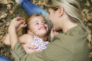 Young mother with herdaughter about smiling.Little girl lying on mother nap.