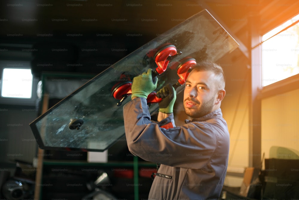 Mechanic changing glass workshop.Looking at camera.