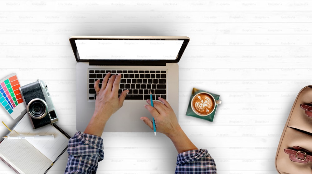 창의적인 창의성 책상 공간 개념. 하얀 나무 책상 위에 노트북에 타이핑하는 남자의 손.
