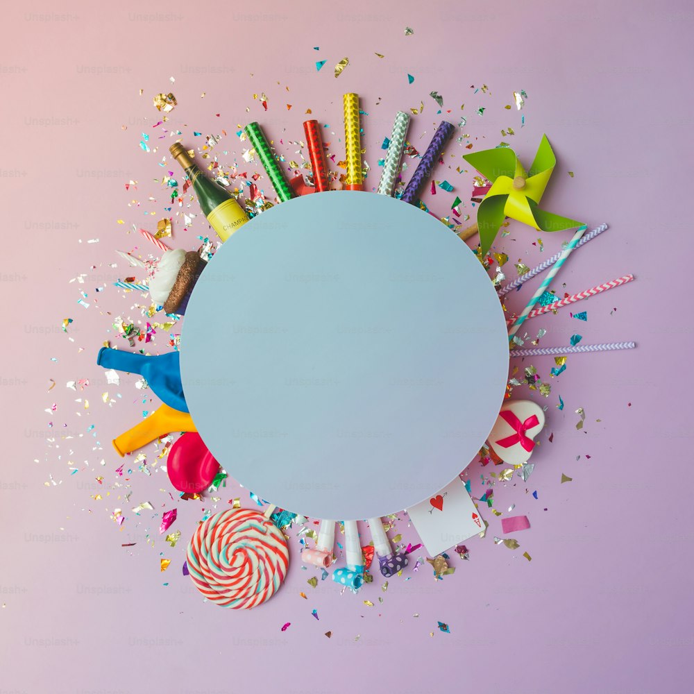 Colorful celebration background with various party confetti, balloons, streamers, fireworks and decoration on pink background. Flat lay.