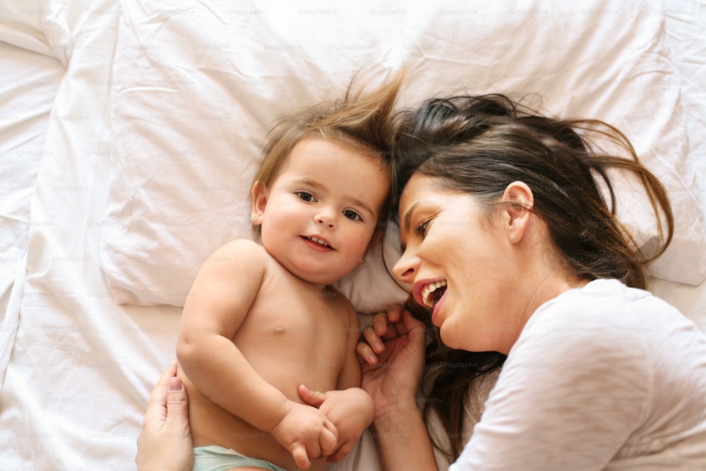 ベッドに横たわる女の赤ちゃんと母親。コピー用のスペース。