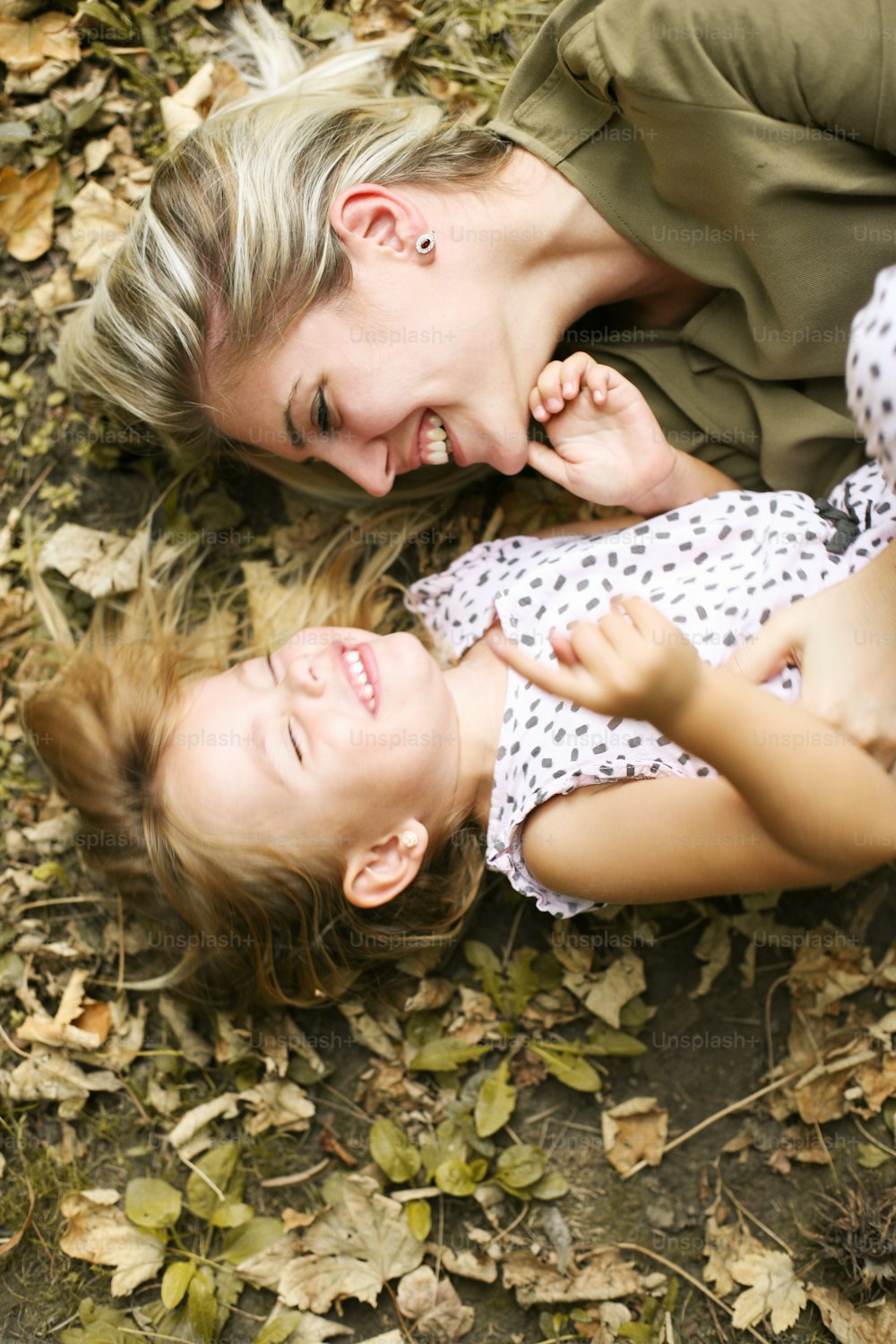 Mother with her daughter lying in the leaves.