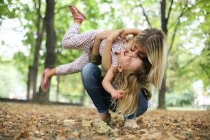 Mother with her daughter playing in the park.Mother hugging her daughter.