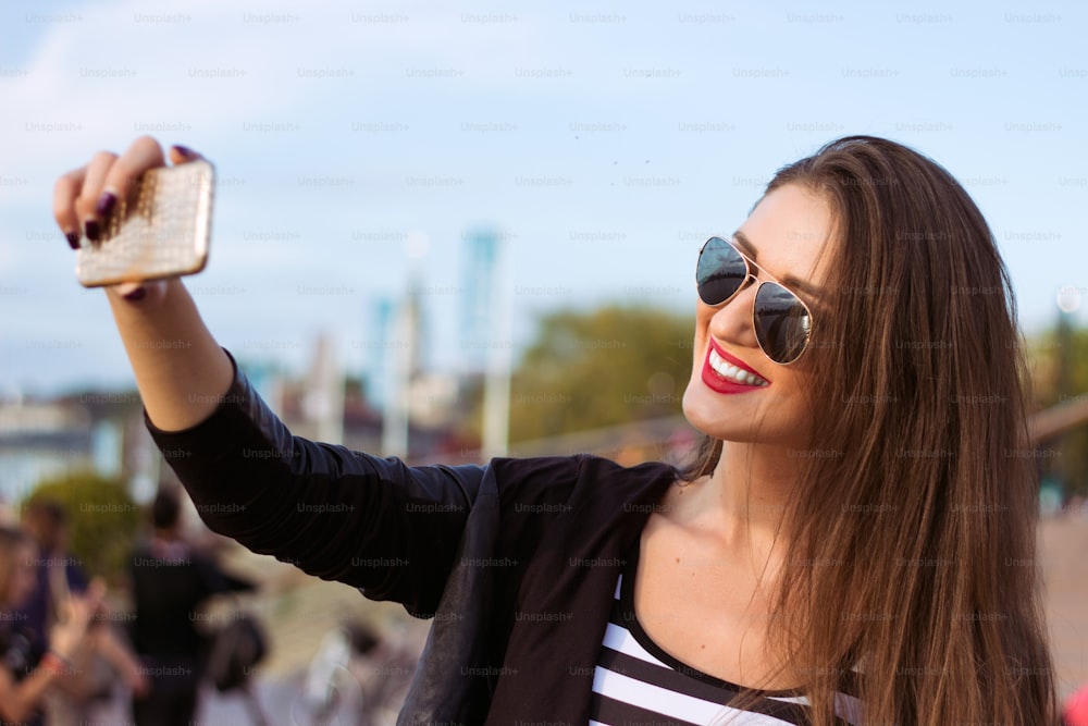 Beautiful urban woman taken picture of herself, selfie. Filtered image.