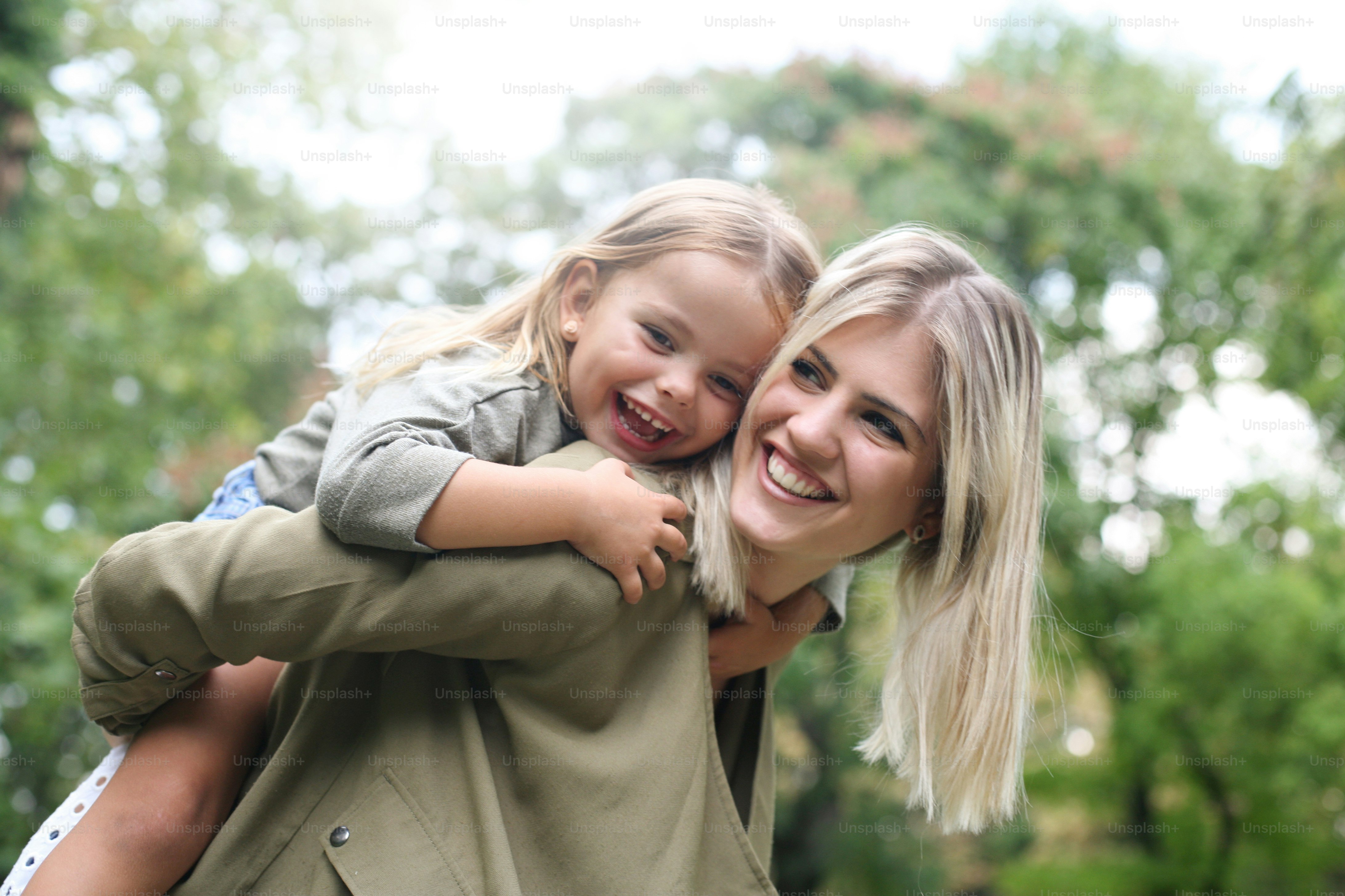 Cute young daughter on a piggy back ride with her mother.