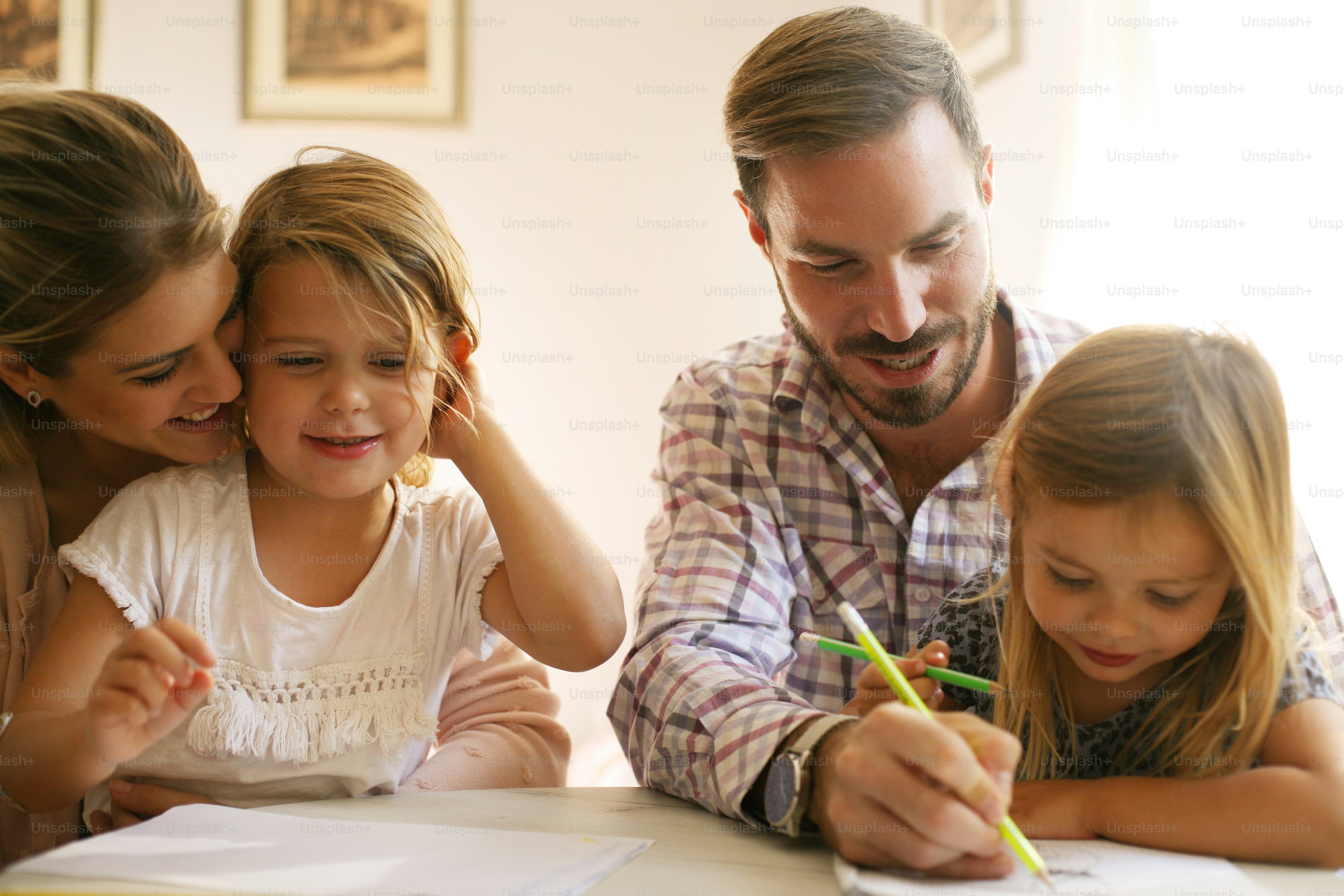 Real family sitting together at home while children draw and learn