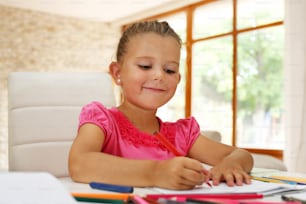 Cute young girl doing her math homework in school work book while sitting at living room table.