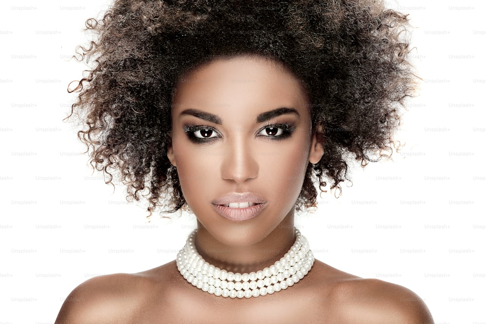 Beauty photo of young elegant african american woman with afro. Girl wearing pearls. Looking at camera. Glamour makeup. Studio shot.