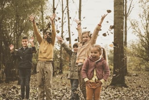 Grupo de niños y niñas jugando en hojas de otoño en el parque.