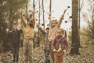 Group of boys and girls playing in fall leaves in the park.