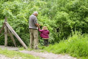 Um avô com sua neta mostrando-lhe algo na floresta.